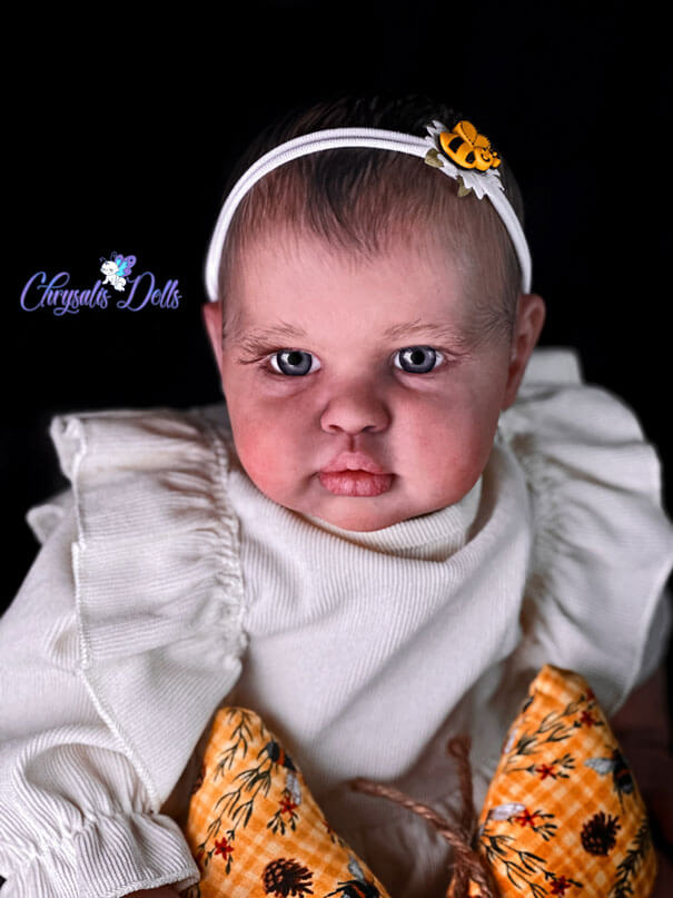 Reborn Ellie wearing a white shirt with her yellow sunflower Guardian Butterfly and matcing bee hair bow.